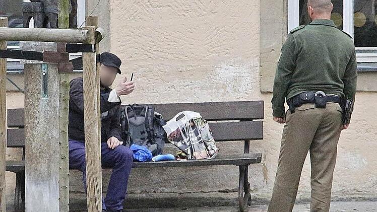 Der Mann zeigt sein Messer, das er immer wieder in die Parkbank rammte. Foto: Josef Hofbauer
