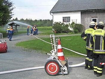 Mitten im Hof dieses Anwesens in Oberp&ouml;llitz befindet sich ein Unterflurhydrant. Aus ihm wurde das Wasser zum "L&ouml;schen" &uuml;ber das neue HLF 20 entnommen. Die Jugendlichen hielten das Strahlrohr fest in den H&auml;nden. Am L&ouml;schfahrzeug die aktiven Feuerwehrm&auml;nner. Foto: Bruno Prei&szlig;inger