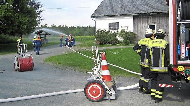 Mitten im Hof dieses Anwesens in Oberp&ouml;llitz befindet sich ein Unterflurhydrant. Aus ihm wurde das Wasser zum "L&ouml;schen" &uuml;ber das neue HLF 20 entnommen. Die Jugendlichen hielten das Strahlrohr fest in den H&auml;nden. Am L&ouml;schfahrzeug die aktiven Feuerwehrm&auml;nner. Foto: Bruno Prei&szlig;inger