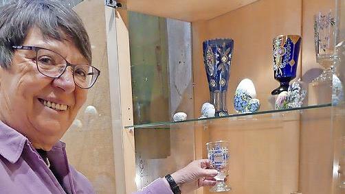 Brigitte Schieder dekoriert eine Vitrine im Museum mit Gläsern und Ostereiern.