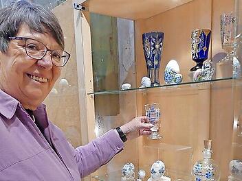 Brigitte Schieder dekoriert eine Vitrine im Museum mit Gläsern und Ostereiern.