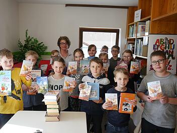 Stolz präsentieren die Viertklässler mit Klassenlehrerin Ursula Schubert ihr Buchgeschenk zum Welttag des Buches. Foto: Oswald Türbl