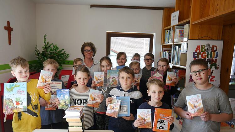 Stolz präsentieren die Viertklässler mit Klassenlehrerin Ursula Schubert ihr Buchgeschenk zum Welttag des Buches. Foto: Oswald Türbl