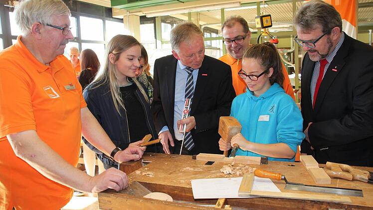 An Schreinerarbeiten versuchen durften sich Hanna Wischniowsky (Zweite von links) aus Burghaig und Lilith Gütling aus Eckersdorf. Bei der Arbeit schauten ihnen über die Schulter (von links) stellvertretender Obermeister Thomas Rosenberger, Kreishandwerksmeister Günther Stenglein, Obermeister Jürgen Bodenschlägel und Thomas Zimmer, Präsident der Handwerkskammer Oberfranken. Fotos: Stephan Stöckel