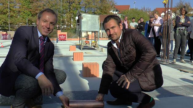 B&uuml;rgermeister Matthias Schneider (links) und Architekt Sebastian Pollach legten zusammen die Zeitkapsel in die daf&uuml;r vorgesehene &Ouml;ffnung im Boden.Christian Licha