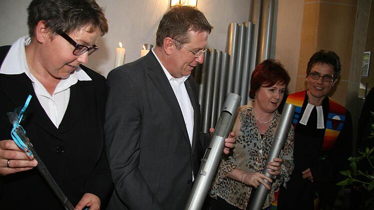 Pfarrerin Godila Baumann, Oberbürgermeister Henry Schramm, Kirchenvorstandsmitglied Christina Flauder und Pfarrerin Bettina Weber (von links) mit einigen der alten Orgelpfeifen.