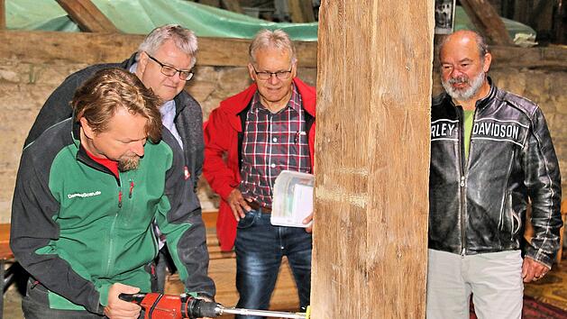 Der Wissenschaftler Georg Br&uuml;tting (links) bohrte L&ouml;cher in zehn Balken der  Zehntscheune in Poppenlauer, um anhand der Bohrkerne das Alter zu  bestimmen.  Interessiert schauten der 2. B&uuml;rgermeister Wolfgang R&uuml;tzel  (2. v. l.), Marktgemeinderat Winfried  Streit (3. v. l.) und Armin Gernert vom Bauamt  der Verwaltungsgemeinschaft Ma&szlig;bach (rechts) ihm &uuml;ber die Schulter.Dieter Britz