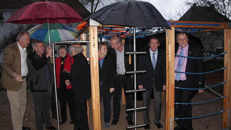 Die Sponsoren, Kinderschutzbeauftragten, Bürgermeister und Landrat bei der Einweihung des Klettergerüsts in strömendem Regen.