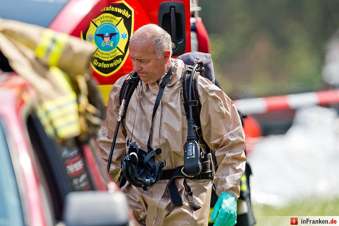 Mit Schutzanzug geht ein Angehöriger des US-Militär am 11.08.2015 bei Engelmannsreuth (Bayern) durch das Einsatzzentrum nahe der Absturzstelle eines Kampfjets. Bei Engelmannsreuth ist ein F-16 Kampfjet der US-Streitkräfte abgestürzt. Foto: Daniel Karmann/dpa
