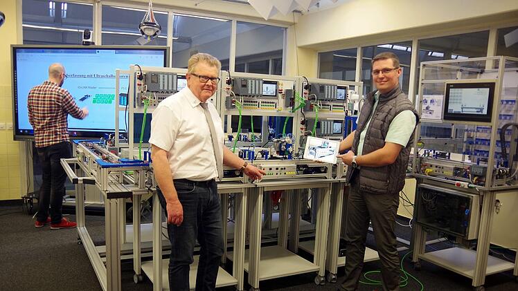 Schulleiter Rudi Schirmer (links) und Studienrat Tobias Kuhnlein vor der hochintelligenten 4.0-Produktionsanlage. Für das Online-Lehrangebot bestand hier die große Herausforderung, die Schüler mittels eines digitalen Zwillings zu beschulen.      Heike Schülein