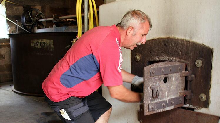 Im Kommun-Brauhaus wird noch mit Holz gefeuert, hier Bernhard Brückner beim Nachlegen. Foto: Bettina Knauth