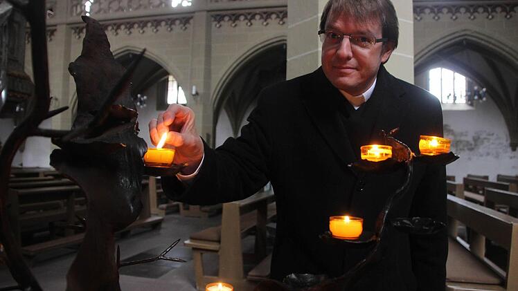 Licht für die Suchenden: Dr. Manfred Bauer zündet am "brennenden Dornbusch" in der katholischen Stadtkirche eine Kerze für diejenigen an, die mit ihrem Glauben hadern.  Foto: Diana Fuchs