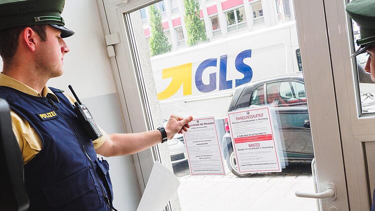 Ein Polizist klebt am 09. Juni in Nürnberg in einen Fahndungsaufruf in verschiedenen Sprachen an eine Tür. Foto: Nicolas Armer/dpa
