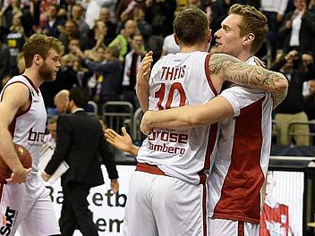 Nicolo Melli (l.) gibt den Ball nicht mehr her, während sich seine Teamkollegen nach der Schlusssirene freudestrahlend in den Armen liegen. Foto: dpa