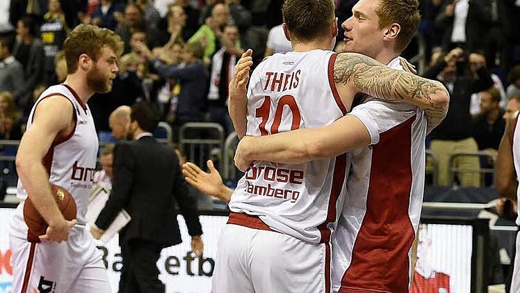Nicolo Melli (l.) gibt den Ball nicht mehr her, während sich seine Teamkollegen nach der Schlusssirene freudestrahlend in den Armen liegen. Foto: dpa