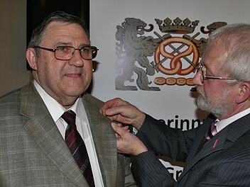 Innungsobermeister Anton Hesselbach steckt Oswin Storath (links) die Ehrennadel des Goldenen Meisterbrief an.  Foto: Vogel