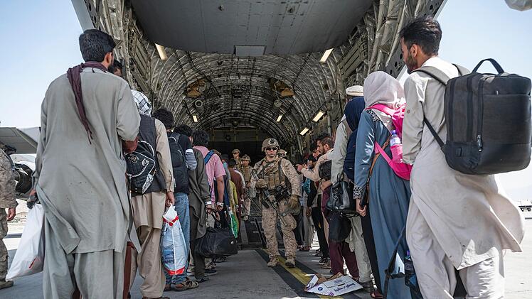 Soldaten geleiten Menschen für die Evakuierung an Bord eines Militärtransportflugzeugs. Auch die Ortskräft, die jetzt in Kulmbach leben, wurde von einer Militärmaschine nach Europa ausgeflogen. Foto: Senior Airman Brennen Lege/U.S. Air Force/AP/dpa