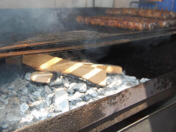Die Brater auf dem Coburger Marktplatz befolgen die Empfehlung der Fleischer-Innung und bereiten die Bratwürste - vorerst - auf Buchenholz statt auf Kiefernzapfen zu. Foto: Oliver Schmidt