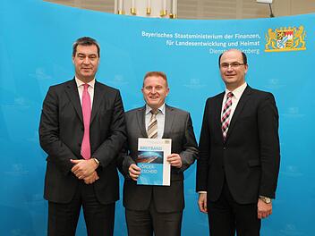 Matthias Klement (Mitte) hat den Förderbescheid aus den Händen von Staatsminister Markus Söder entgegengenommen. Rechts: Albert Füracker ,Staatssekretär im Bayerischen Staatsministerium der Finanzen, für Landesentwicklung und Heimat. Foto: Bayerisches Finanzministerium
