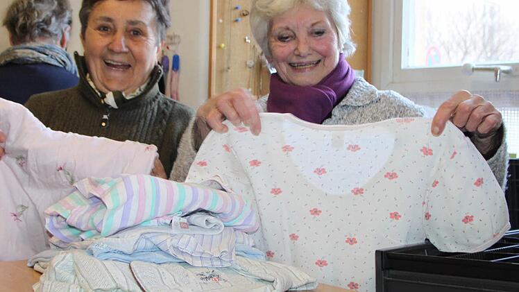 Gisela Hofbauer (links) und Marie-Luise Geyer sortieren Schlafanzüge. Im Hintergrund hilft Christa Gayer. Sie alle gehören zum Helferteam des Caritas-Kramlädchens in Bad Brückenau. Foto: Ulrike Müller