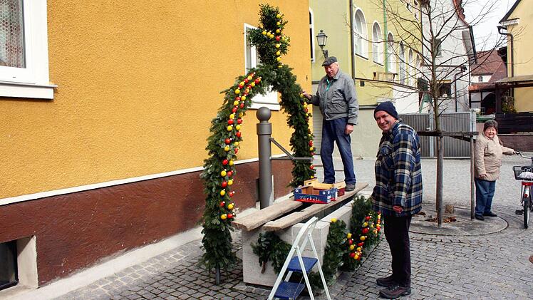 Der neue, im Zuge der Altstadtsanierung geschaffene Brunnen in der Marienstraße soll auch nicht ohne Schmuck auskommen müssen, finden Walter (links) und Brigitte Hemmerlein (rechts). Nachbar Michael Gessler (Mitte) geht ihnen zur Hand.
