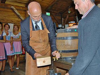 Oberbürgermeister Kay Blankenburg (links) zapft das erste Fass Bier in der Oktoberfest-Hüttn an.  Foto: Sigismund von Dobschütz