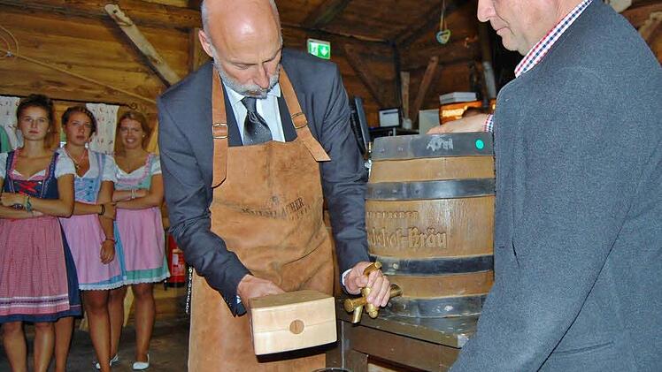 Oberbürgermeister Kay Blankenburg (links) zapft das erste Fass Bier in der Oktoberfest-Hüttn an.  Foto: Sigismund von Dobschütz