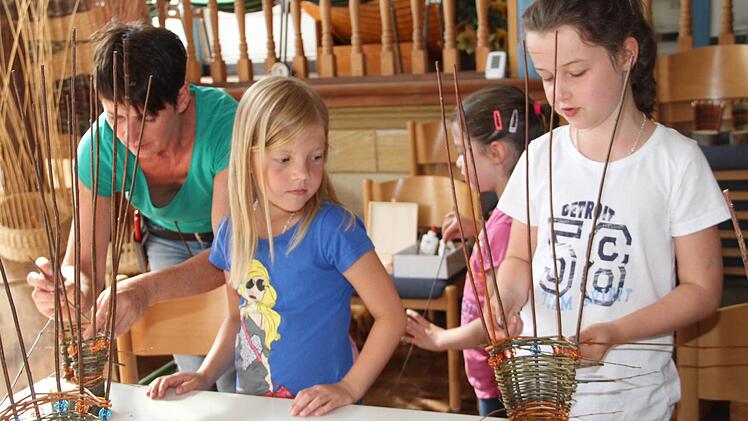 Unter der Anleitung von Flechtwerkgestalterin Gitti Klitzner (links) sind Jule (Zweite von links) und Amelie (rechts) mit Eifer bei der Sache.  Foto: Gerda Völk