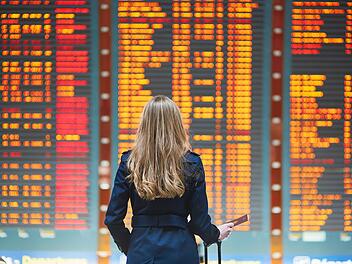 Junge Reisende am internationalen Flughafen  Young woman in international airport looking at the flight information board, holding passport in her hand, checking her flight Young female  traveler in international airport  von Ekaterina Pokrovsky Abflugtafel / Ankunftstafel Fluginformationsanzeige (FIDS) &ndash; Flight Information Display System Anzeigetafel (allgemein) Flugplananzeige Flugdatenanzeige Monitore / Bildschirme (die Flugdaten anzeigen)