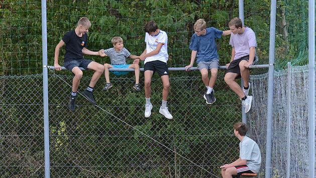 Beim Kreisliga-Match zwischen dem gastgebenden VfR Sulzthal und FV Rannungen/Pfändhausen/Holzhausen suchen sich die heimischen Jugendlichen einen besonderen Sitzplatz und helfen dem Jüngsten beim Aufstieg auf den Zaun. Die Partie endete  übrigens ...