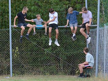Beim Kreisliga-Match zwischen dem gastgebenden VfR Sulzthal und FV Rannungen/Pfändhausen/Holzhausen suchen sich die heimischen Jugendlichen einen besonderen Sitzplatz und helfen dem Jüngsten beim Aufstieg auf den Zaun. Die Partie endete  übrigens ...