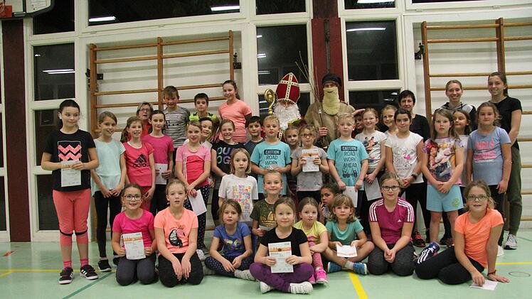 Strahlend halten die Mädchen und Jungs die Sportabzeichen in Händen. Die hatten der Nikolaus und Knecht Ruprecht für die Sechs- bis Elfjährigen mitgebracht, die in der Leichtathletikabteilung beim TV/DJK Hammelburg trainieren.  Foto: Angelika Silberbach