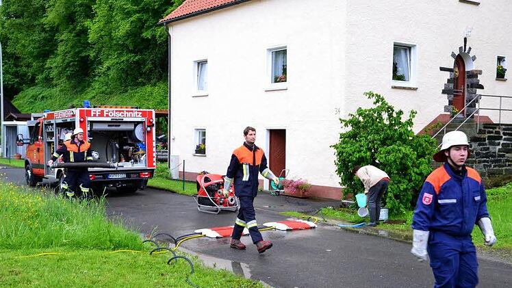 Die Feuerwehr schließt erste Pumpen an. Derweil schöpfen die Bewohner mit Eimern den Gully vor dem Haus aus, damit die Waschküche nicht absäuft.