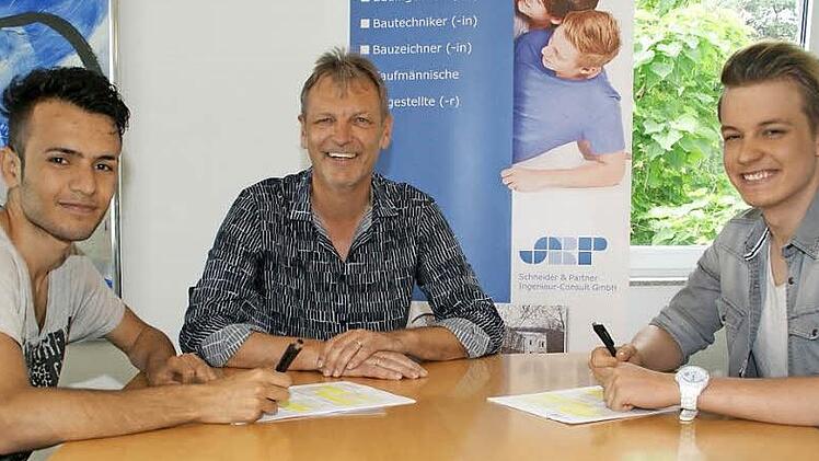 Unterschrift für einen neuen Lebensabschnitt: In Zeil beginnen am 1. September ihre Ausbildung zum Bauzeichner Julian Kehl aus Zeil (rechts) und Hani Shaker aus Mossul (links). Chef Hans-Joachim Brandt hat für den jungen Flüchtling einen Ausbildungsplatz geschaffen.  Fotos: Sabine Weinbeer