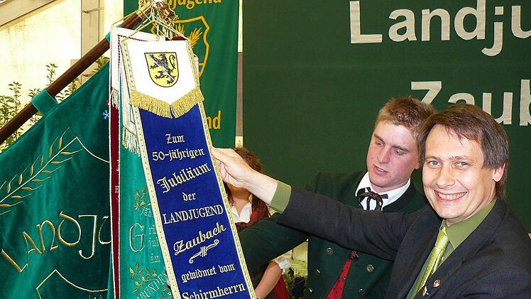 Bürgermeister Roland Wolfrum (rechts) heftete zur Erinnerung an die Festtage ein Fahnenband an die Standarte der Landjugend.