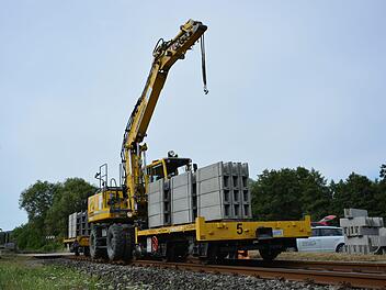 Ein Kran auf Schienen verlegt die vorgefertigten Betonteile entlang der Bahnstrecke zwischen Burglauer und Mellrichstadt. Am Samstag sollen die Arbeiten abgeschlossen sein.  Foto: Björn Hein