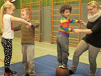 Gleichgewicht halten ist hier gefragt auf dem Medizinball, wobei Hilfe von den Größeren gefragt ist; von links Viola, Marc, Taye mit Erzieherin Tanja Schwarz. Foto: Günther Geiling
