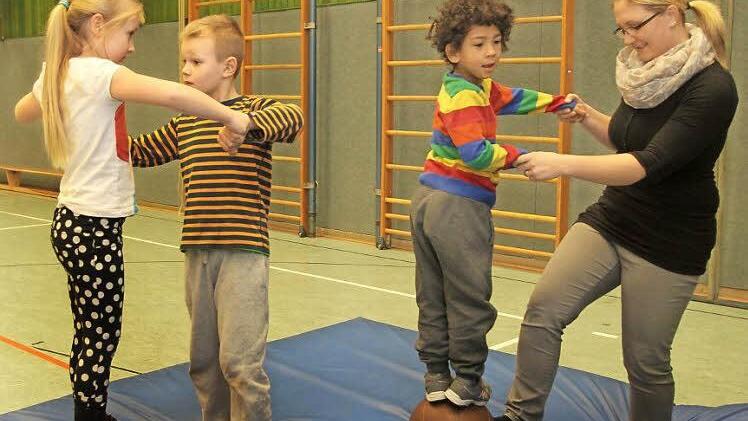 Gleichgewicht halten ist hier gefragt auf dem Medizinball, wobei Hilfe von den Größeren gefragt ist; von links Viola, Marc, Taye mit Erzieherin Tanja Schwarz. Foto: Günther Geiling
