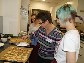 "Jetzt müssen die Plätzchen noch heiß vorsichtig in den Zucker gedrückt werden", erklärte Marianne den beiden Berufsfachschülerinnen Katharina und Ina. Foto: Sabine Weinbeer