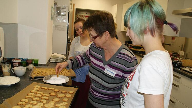 "Jetzt müssen die Plätzchen noch heiß vorsichtig in den Zucker gedrückt werden", erklärte Marianne den beiden Berufsfachschülerinnen Katharina und Ina. Foto: Sabine Weinbeer