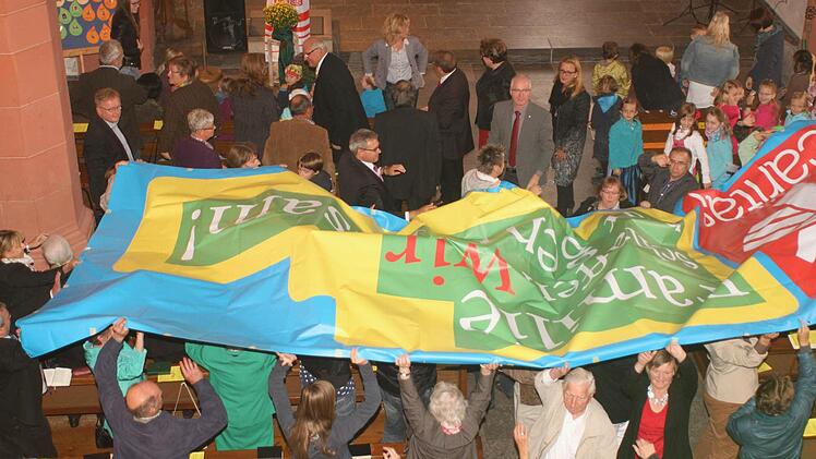 Viele Hände trugen das Banner mit der Aufschrift "Familie schaffen wir nur gemeinsam" durch die Stadtpfarrkirche Haßfurt. Fotos: Günther Geiling