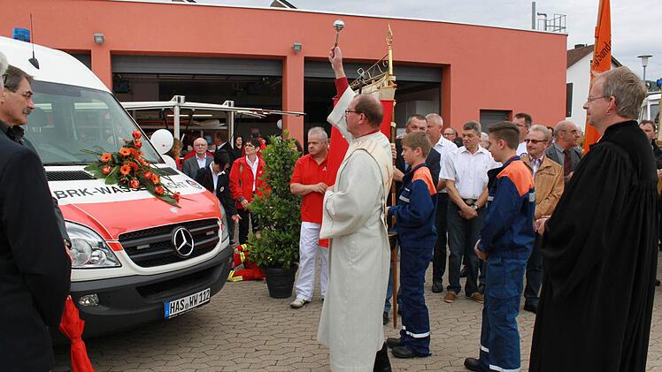 Diakon Bernhard Trunk (links) und Pfarrer Hans-Christian Neiber (rechts) haben sowohl den Erweiterungsbau der Feuerwehr als auch das neue Einsatzfahrzeug der Wasserwacht (im Bild) unter Gottes Segen gestellt.