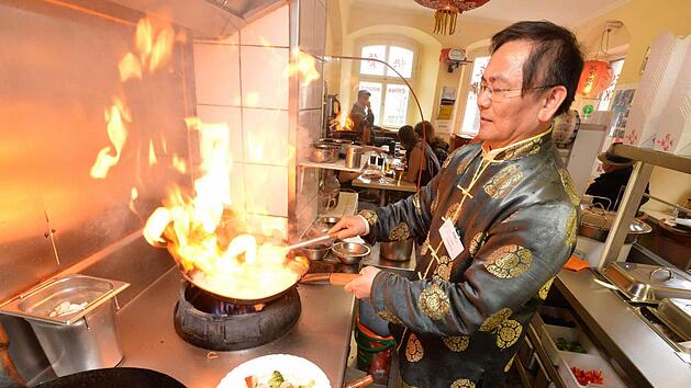 Ein Koch in dekorativer Kleidung flambiert Speisen in einer Imbissk&uuml;che. Anl&auml;sslich der Zeugnisvergabe gibt es besondere Aktionen f&uuml;r Sch&uuml;ler.