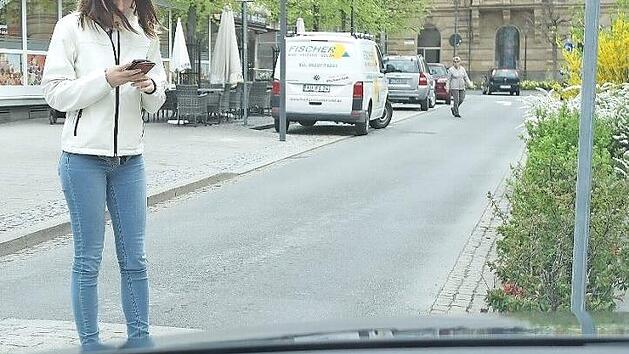 Redaktionspraktikantin Maria Schulze aus Wonsees zeigt, wie man es nicht machen sollte: Mit dem Blick auf ihr Smartphone überquert sie die Straße beim "Fritz"-Einkaufszentrum. Foto: Peter Müller