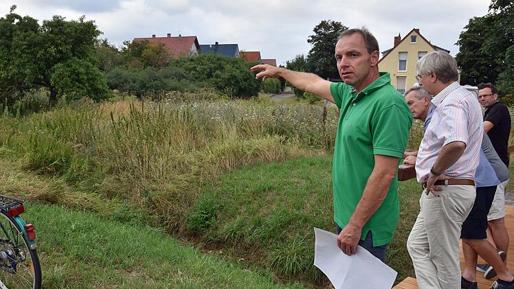 Die Gemeinde Theres möchte auf einigen ihrer Flächen entlang des Riedengrabens in Obertheres Rückhaltungen für Starkregenereignisse schaffen. Bürgermeister Matthias Schneider (vorne) deutet auf eine Fläche nach der Brücke am "Rentnerweg".