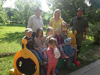 250 Euro gibt es für eine Matschecke. Über die Spende, die Georg Zänglein Junior und Georg Zänglein Senior überreichten, freuen sich die Kindergartenkinder mit Leiterin Waltraud Schott. Foto: Stefan Geiger