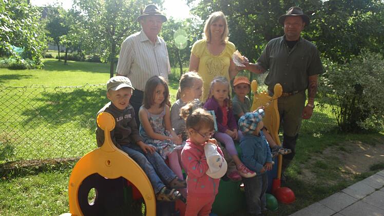 250 Euro gibt es für eine Matschecke. Über die Spende, die Georg Zänglein Junior und Georg Zänglein Senior überreichten, freuen sich die Kindergartenkinder mit Leiterin Waltraud Schott. Foto: Stefan Geiger