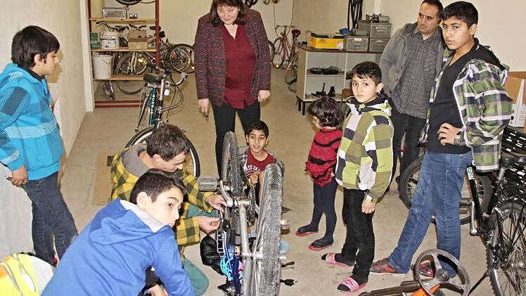 Neugierig schauen die Kinder Thomas Herrmann (am Fahrrad) auf die Finger. Sie wollen auch lernen, wie man Fahrräder repariert. Hinten beobachtet Claudia Fischer-Curdts, Leiterin der Personalentwicklung bei FTE, die Szenerie. Foto: Helmut Will