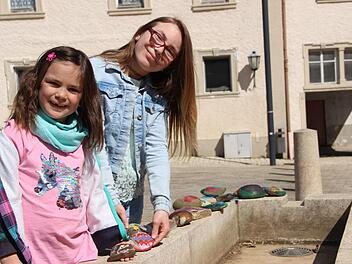 Leni (links) und Emelie Dittmar haben Spaß daran, Steine zu bemalen und diese am Marktplatz in Maßbach zu dekorieren. Foto: Heike Beudert