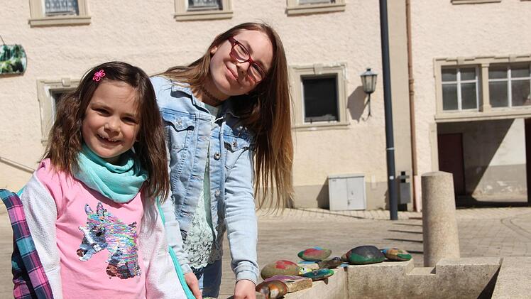 Leni (links) und Emelie Dittmar haben Spaß daran, Steine zu bemalen und diese am Marktplatz in Maßbach zu dekorieren. Foto: Heike Beudert